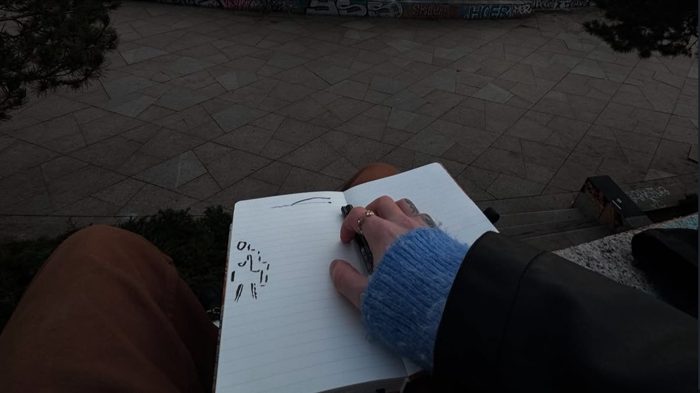 Sketching in a notebook on a park bench