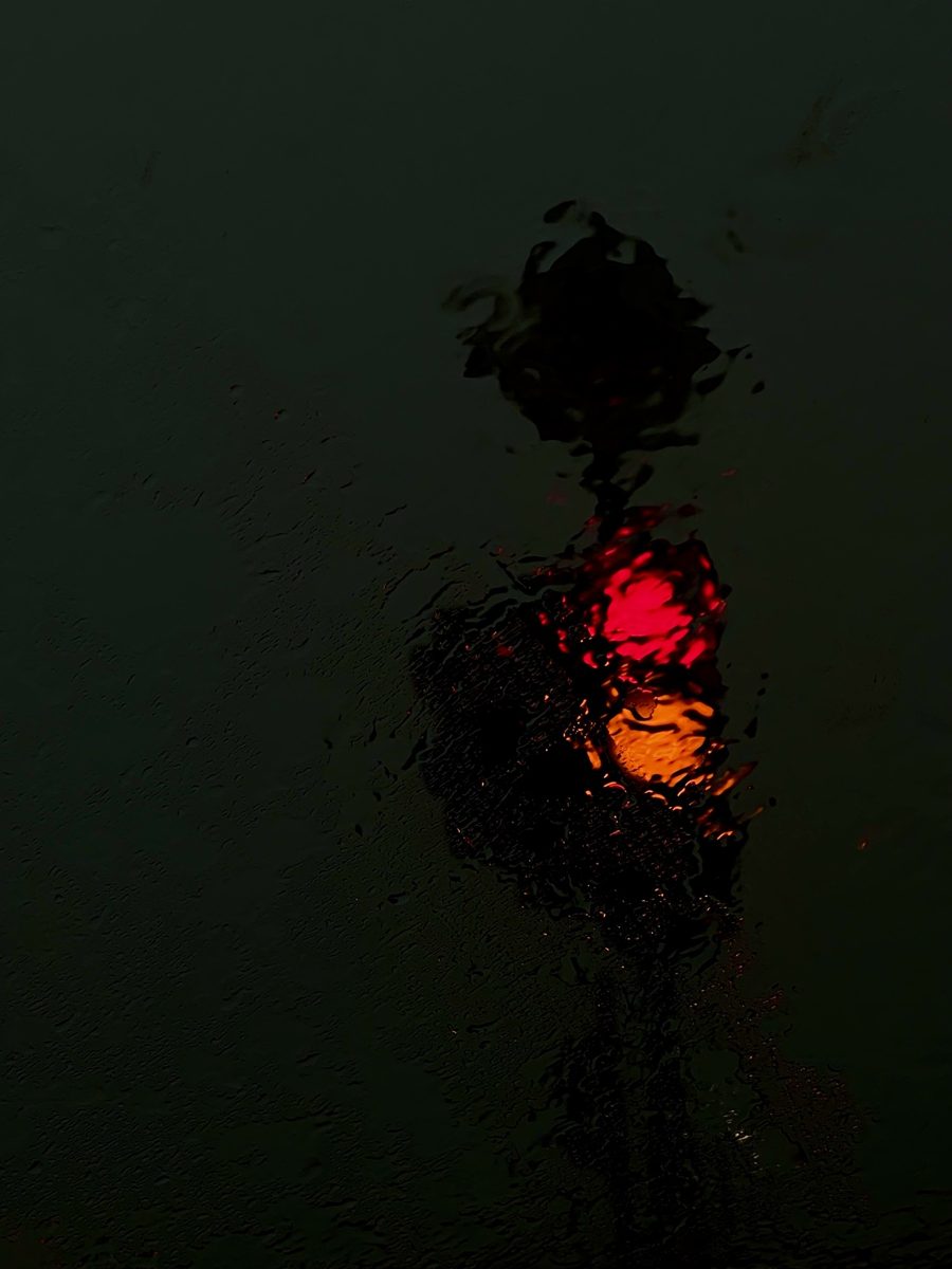 A red traffic light through a rainy windscreen