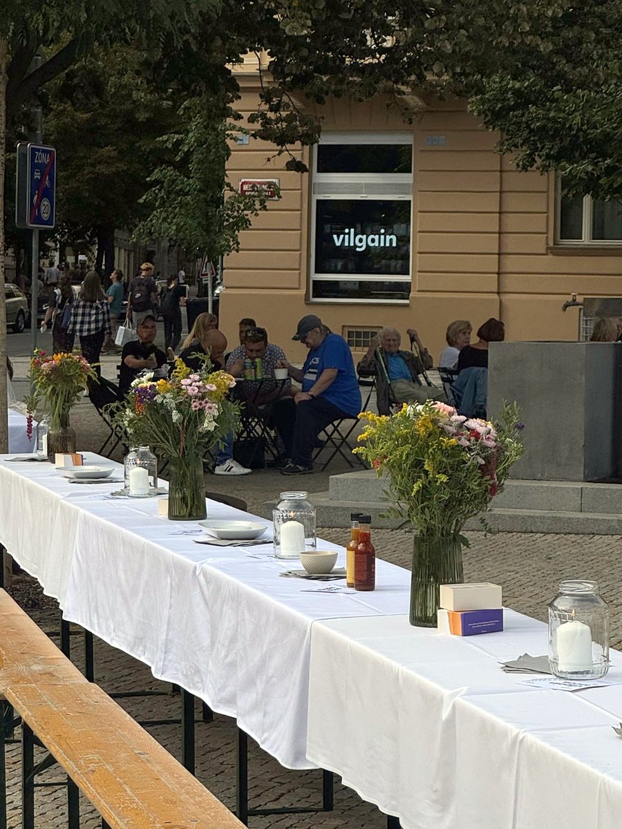 The long table on Jiřák before the guests arrive, with the Vilgain store behind the trees